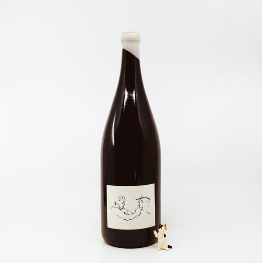 black wine bottle with white topper and white label next to cat figurine