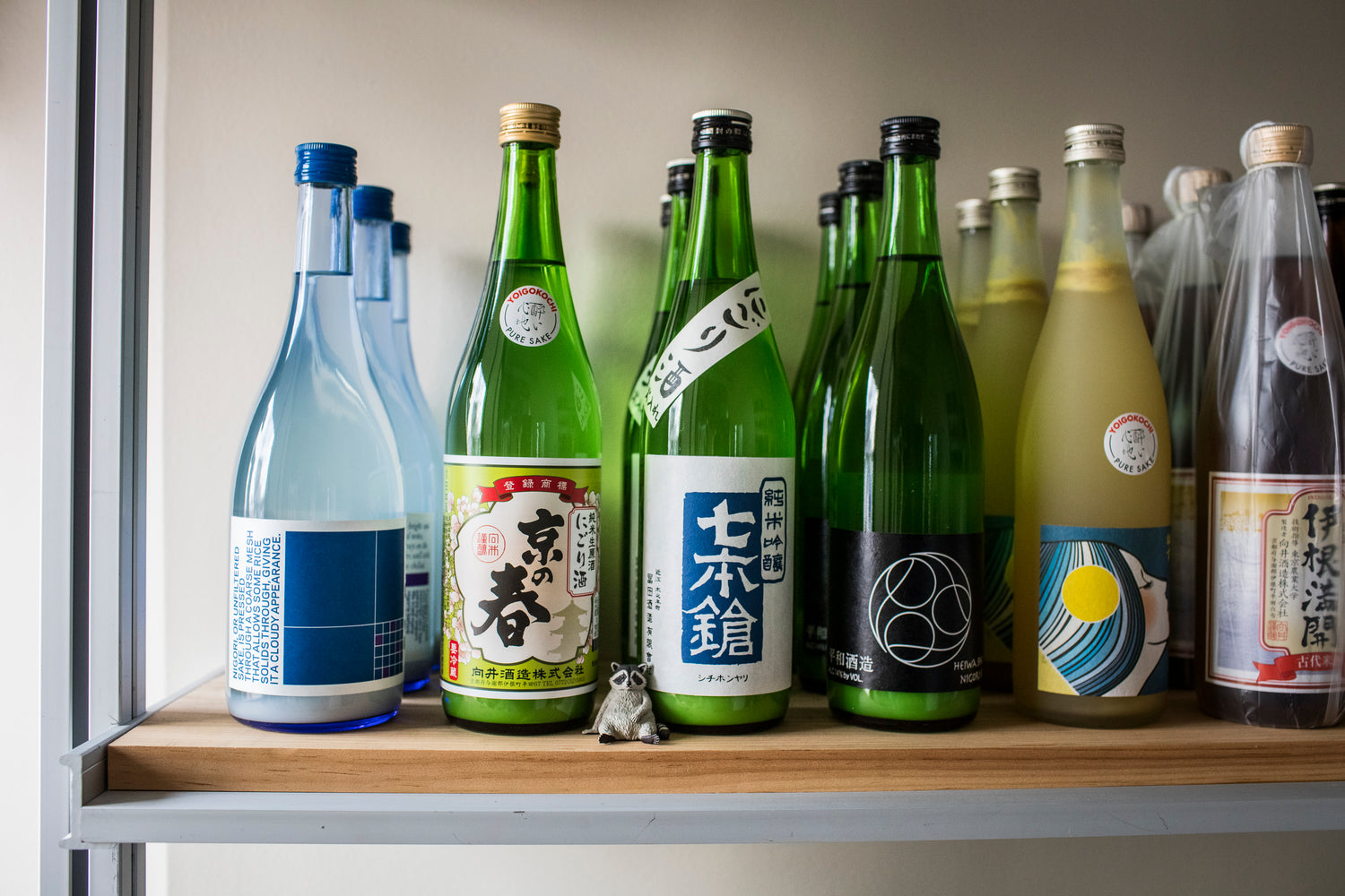 bottles on a shelf with raccoon figurine