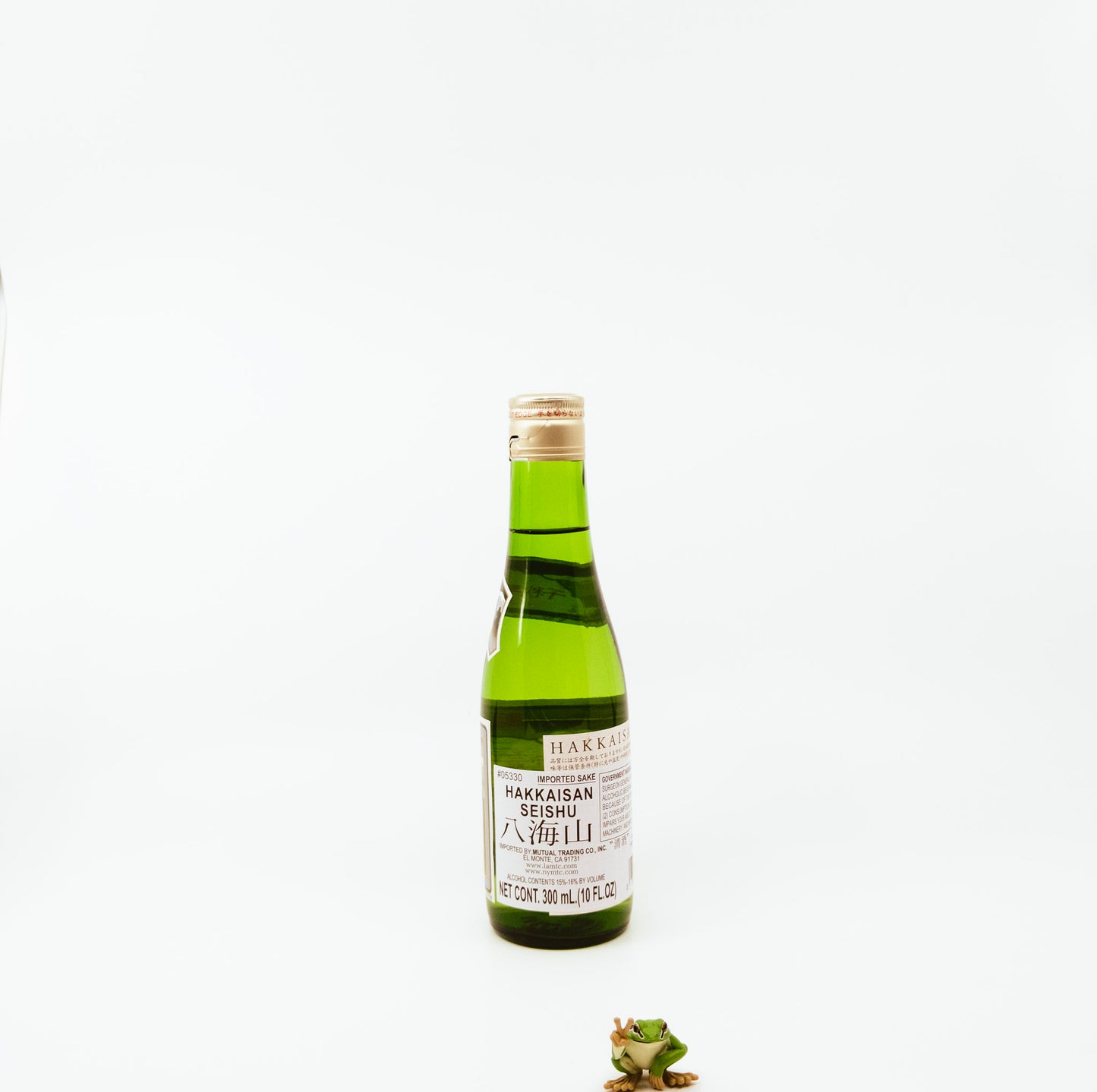 back of short green bottle next to frog figurine