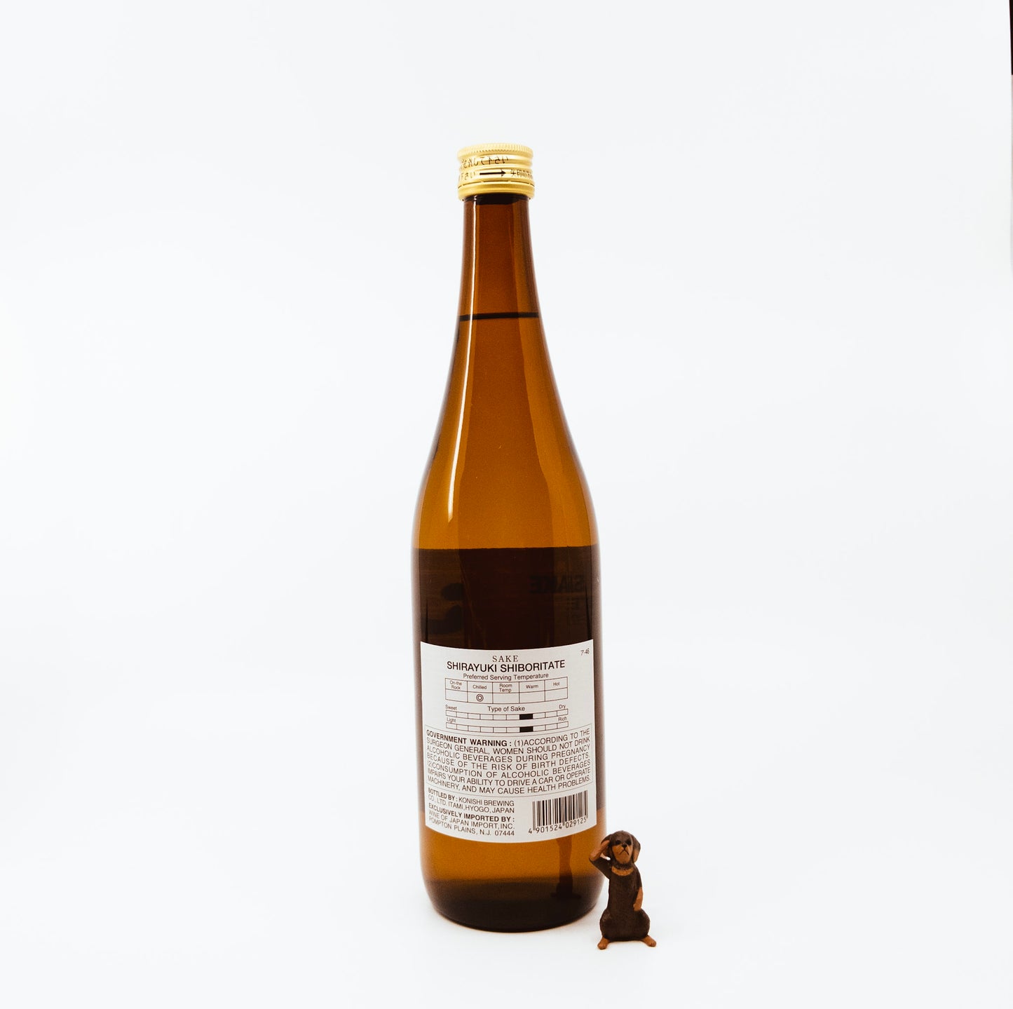 back of brown bottle next to monkey figurine