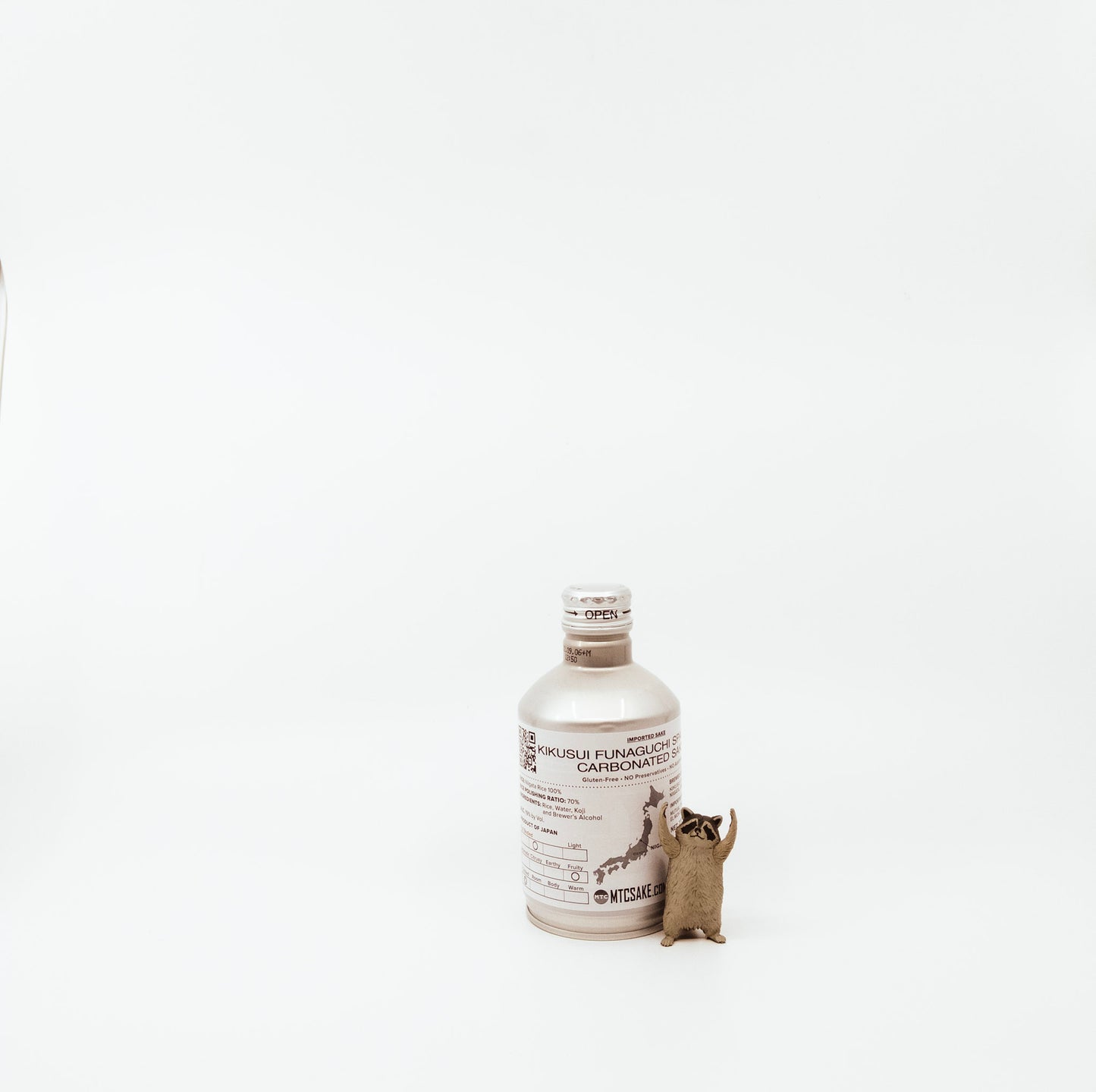 back of small white bottle next to raccoon figurine
