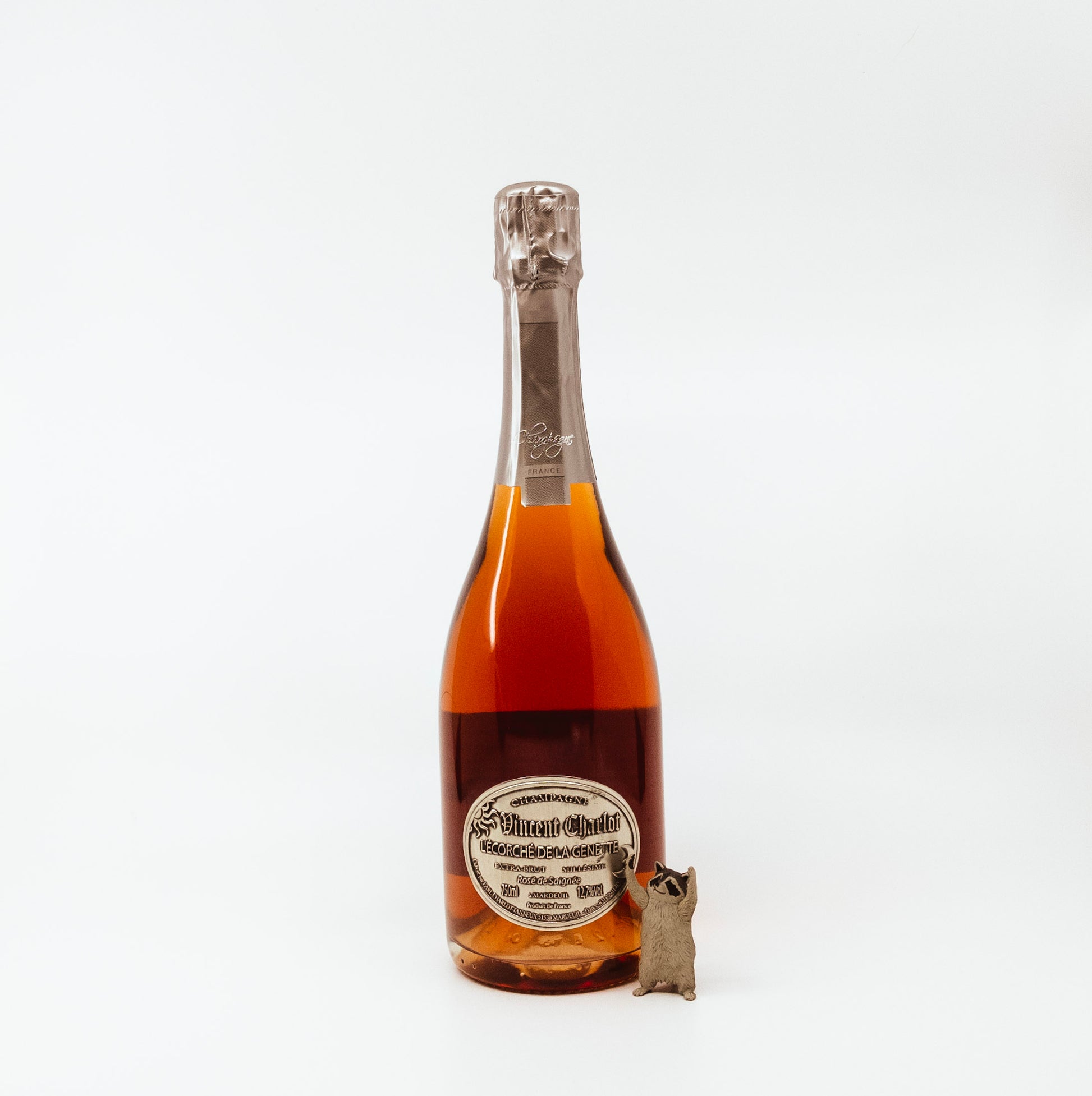 glass bottle with circle label and raccoon figurine