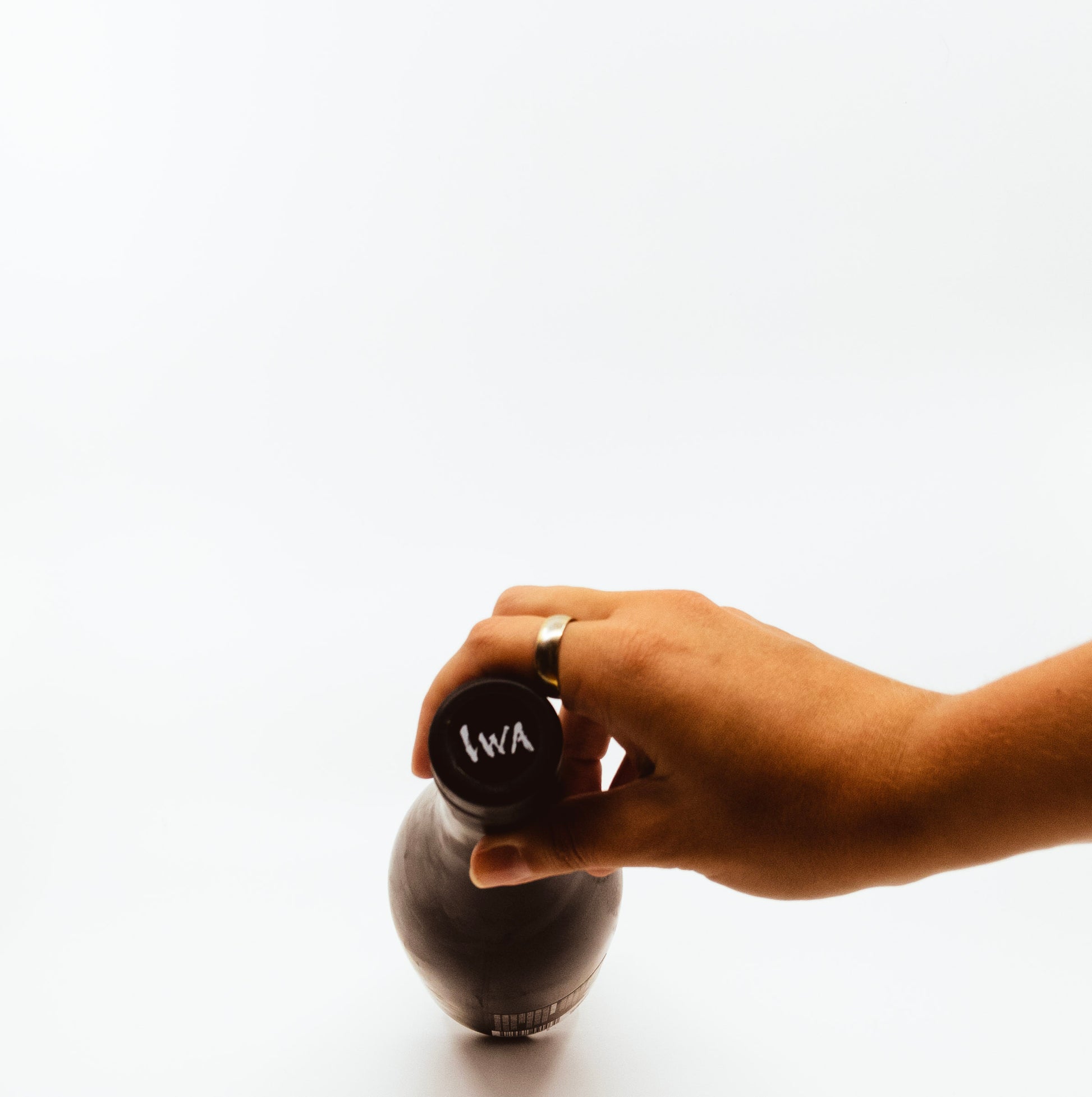 person holding tip of black glass bottle