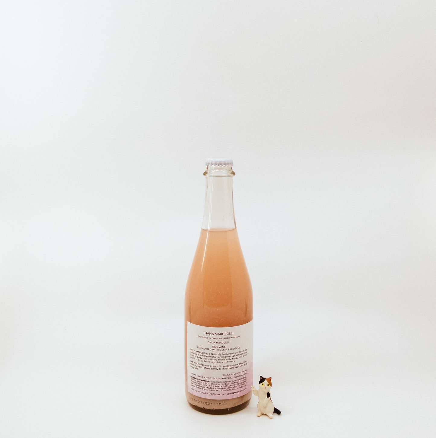 back of glass bottle next to cat figurine
