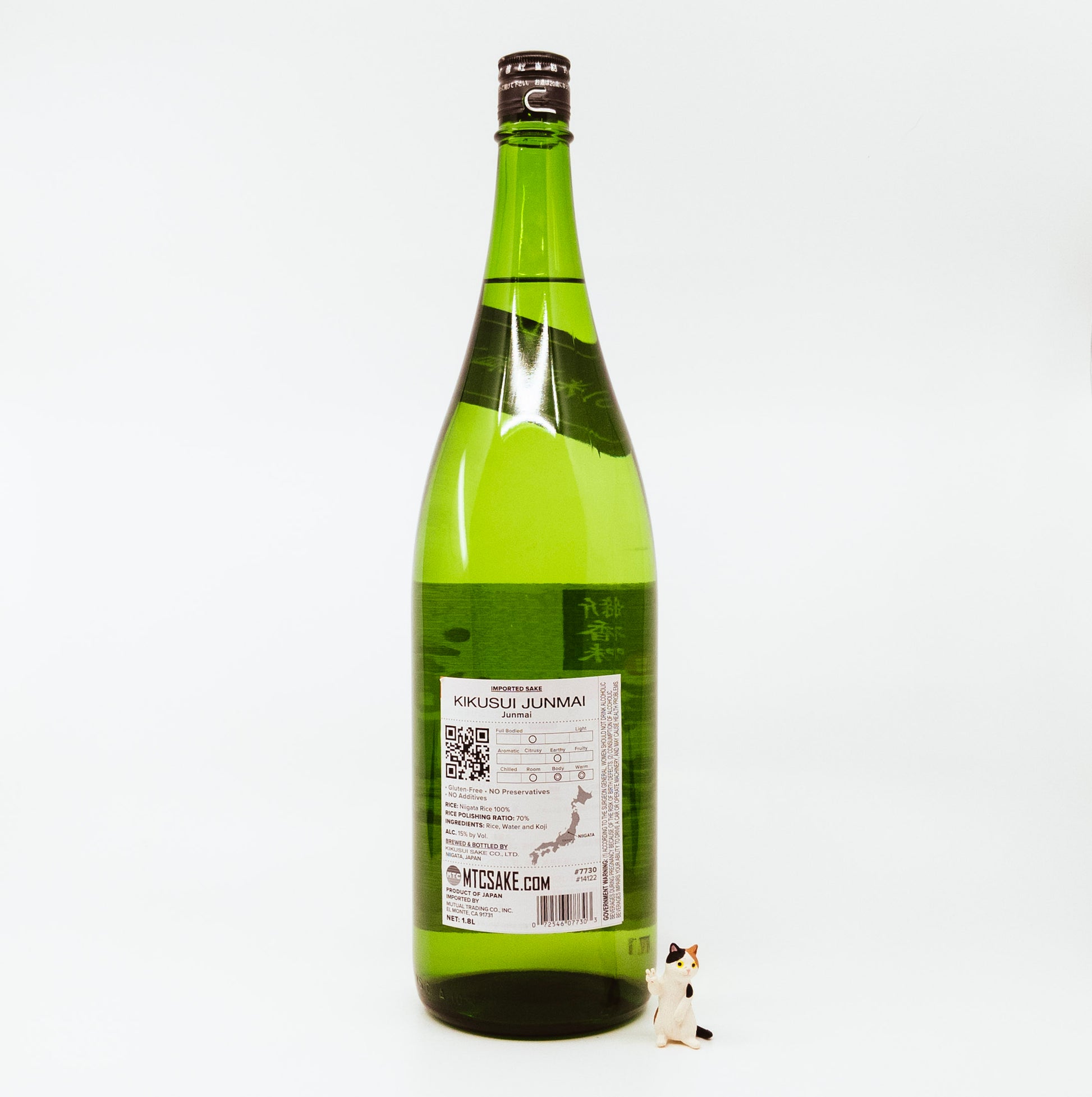 back of green bottle with cream label next to cat figurine