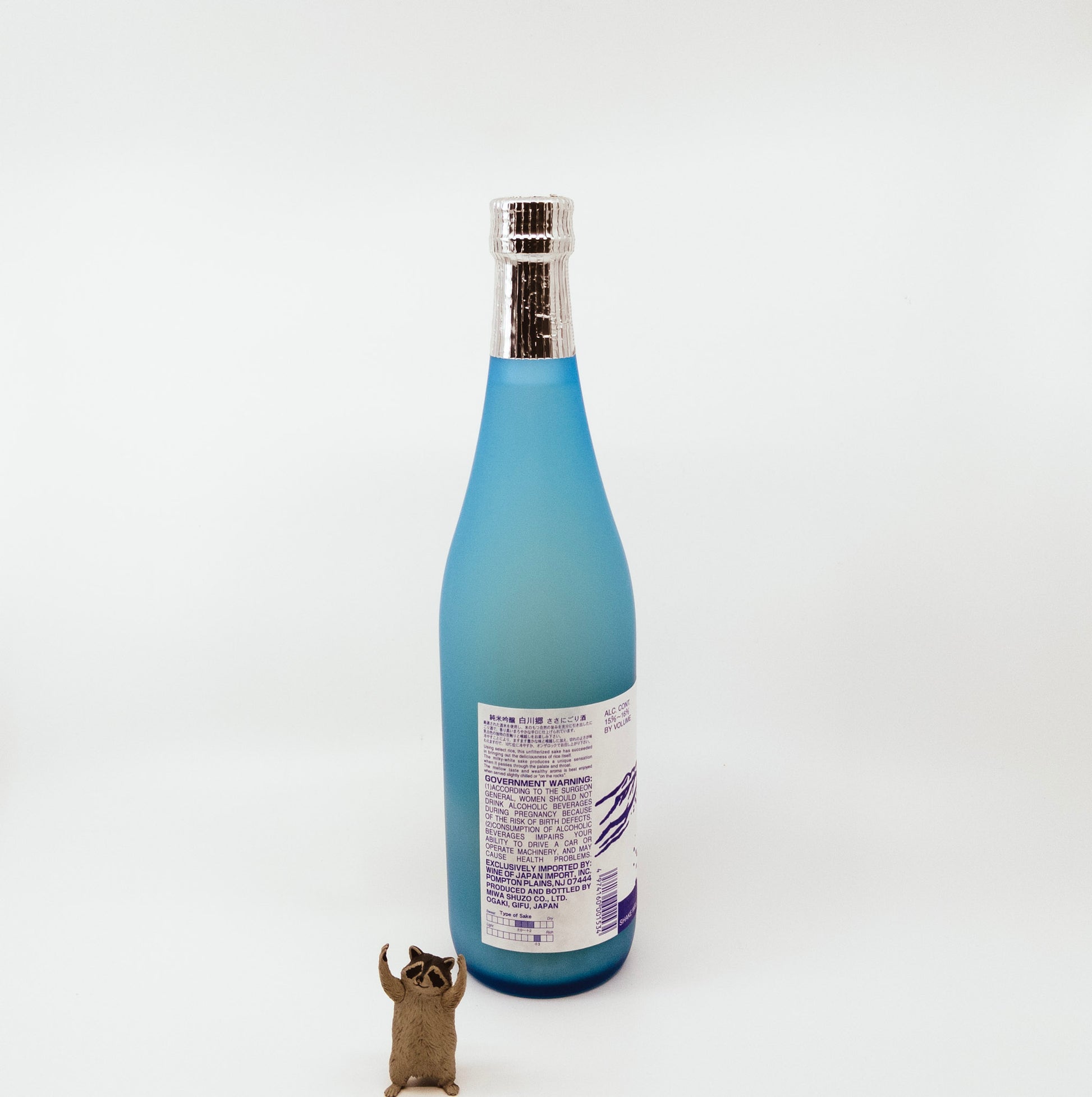 back of blue glass bottle next to raccoon figurine