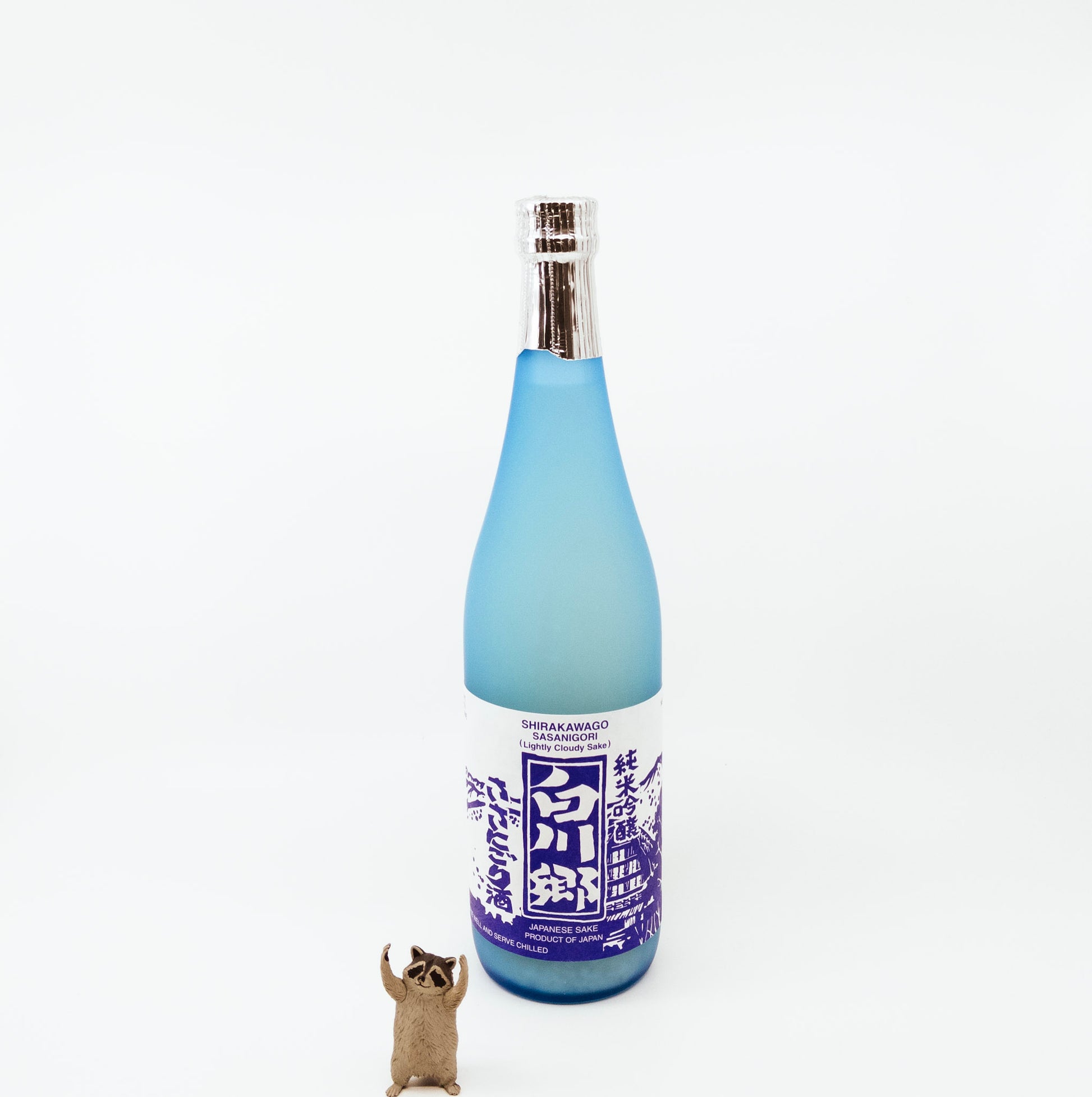 blue glass bottle next to raccoon figurine