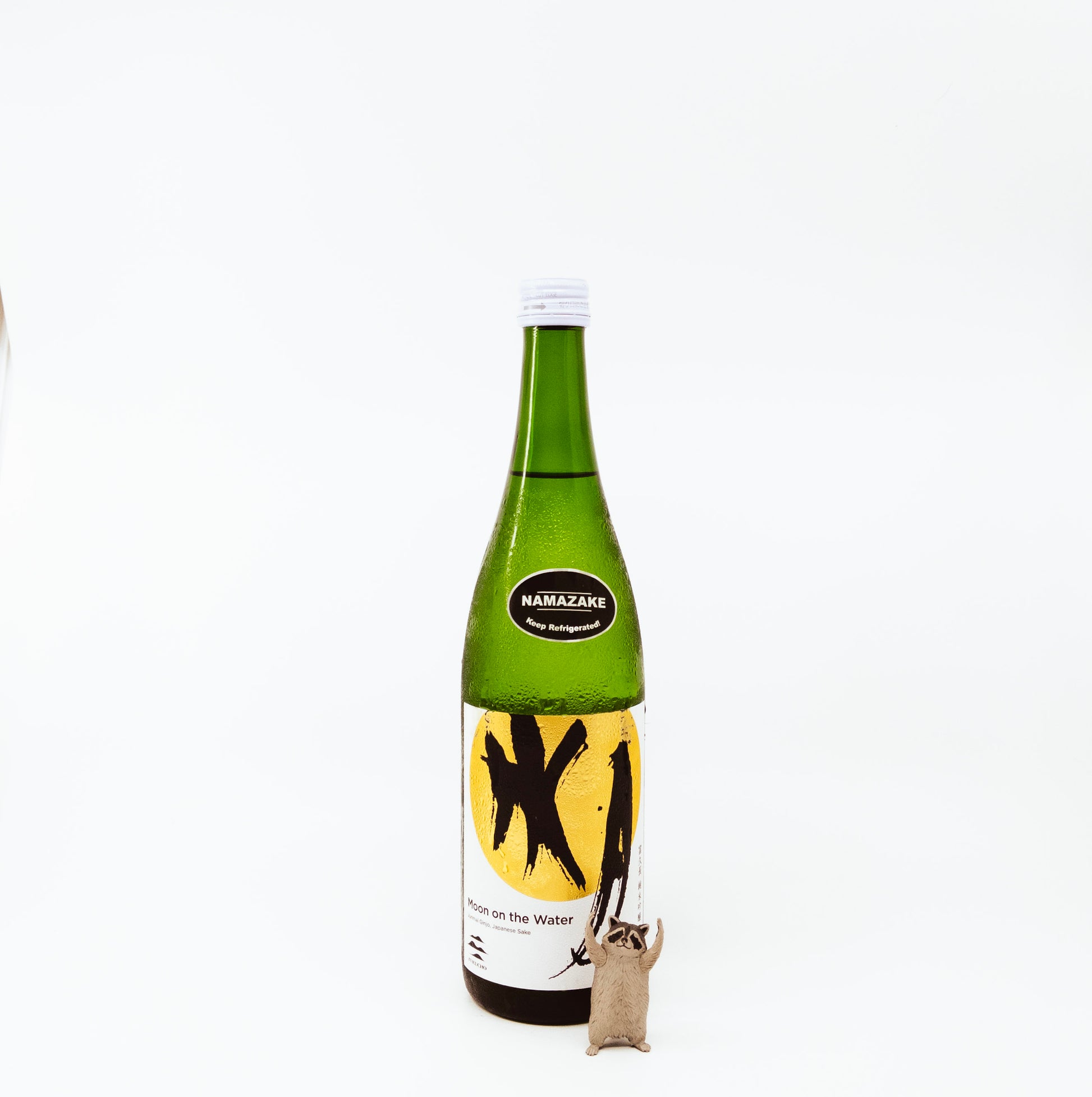 glass bottle next to raccoon figurine