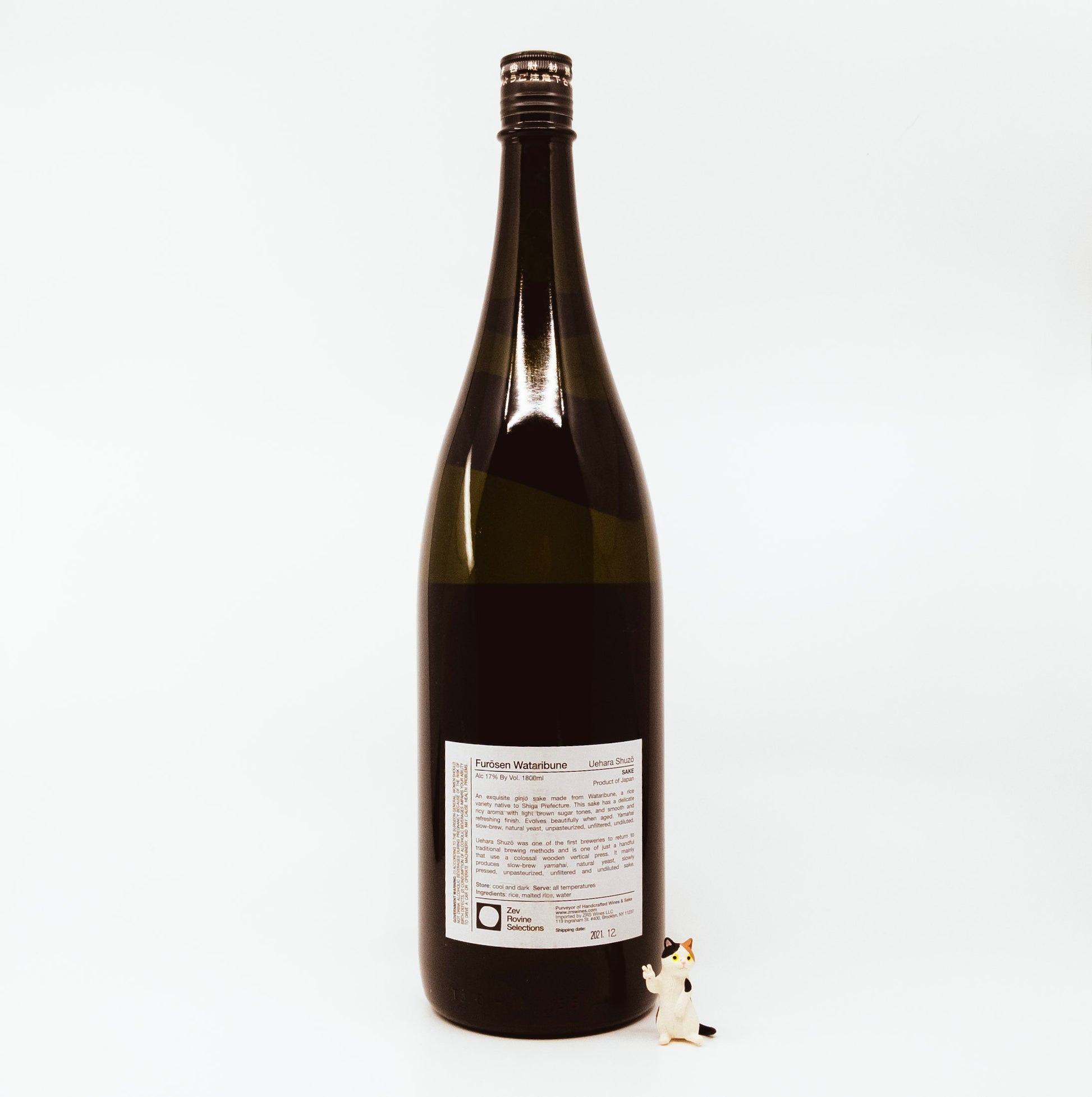 back of brown glass bottle with cat figurine next to it