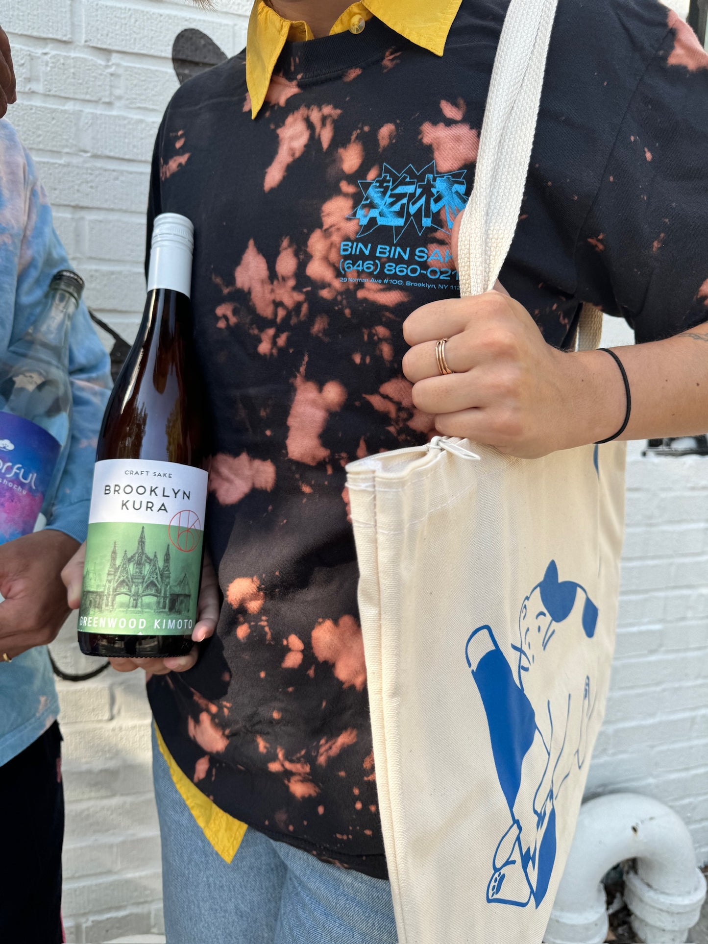 person holding wine bottle and tote bag