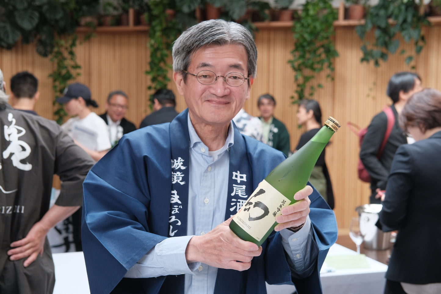older man holding up a green bottle