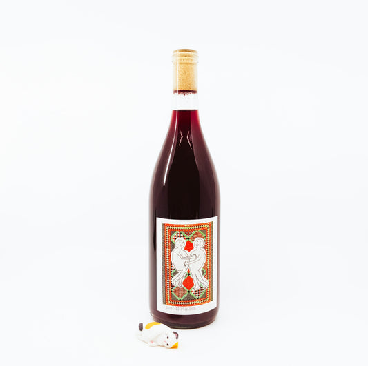 bottle with two people on colorful label next to cat figurine