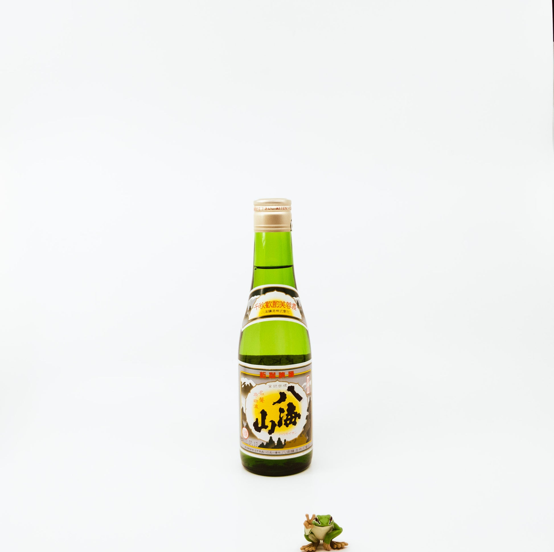 short green bottle next to frog figurine