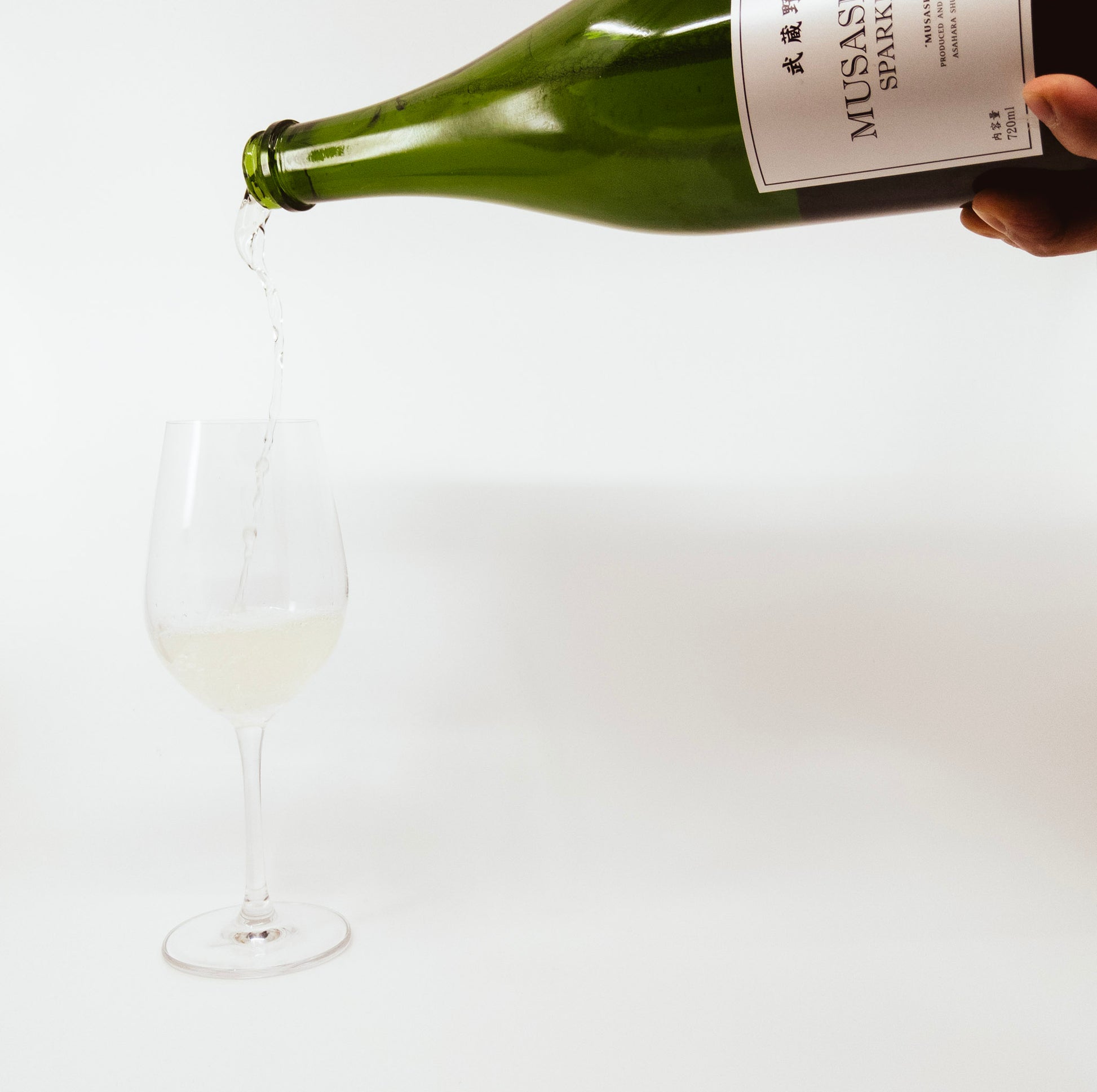 person pouring bottle of wine into wine glass