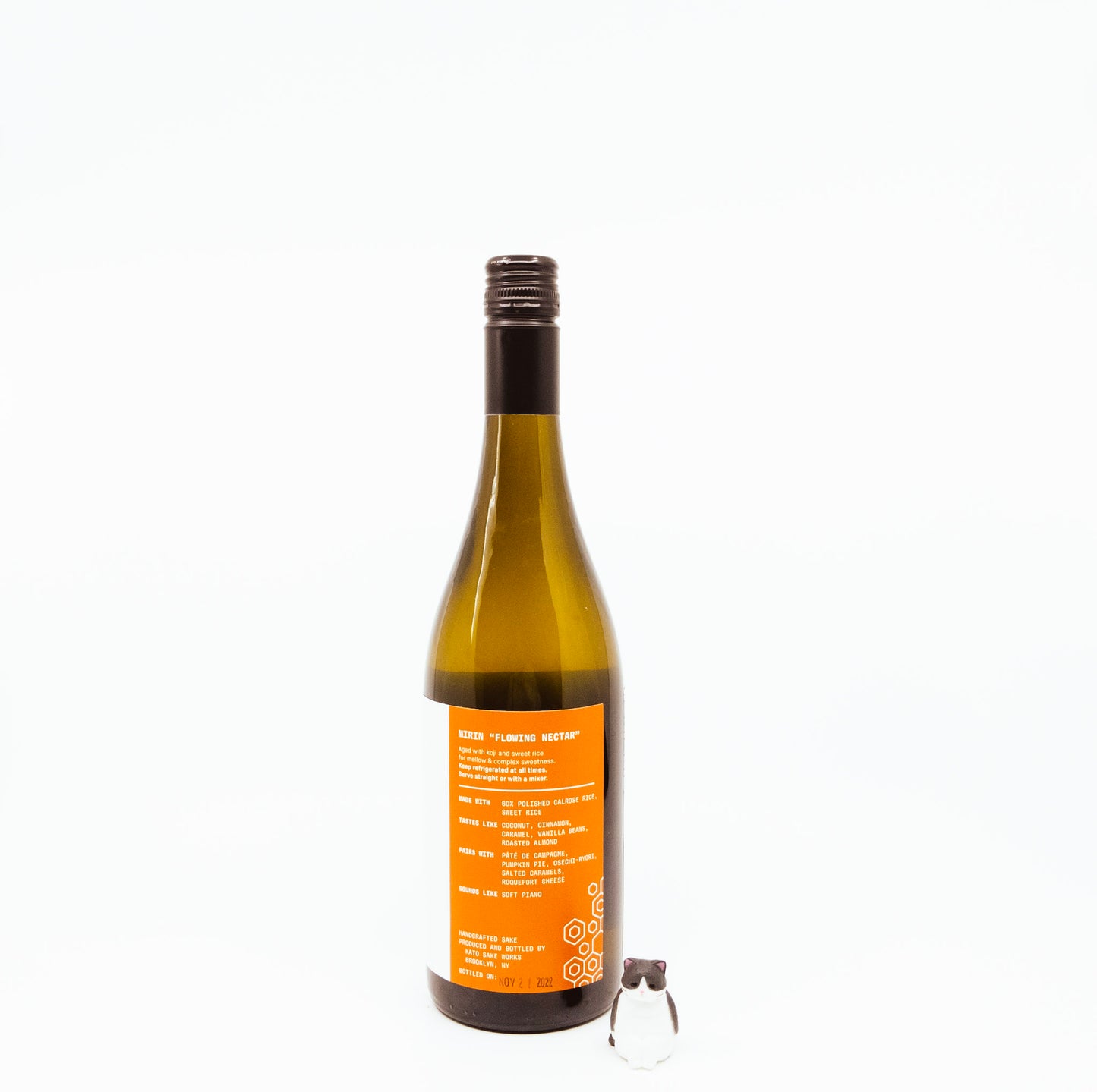 back of bottle with orange logo on label next to cat figurine