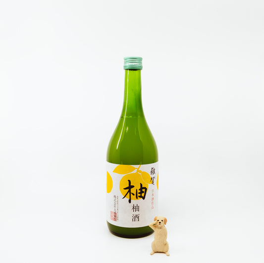 green glass bottle with yellow on white label next to dog figurine