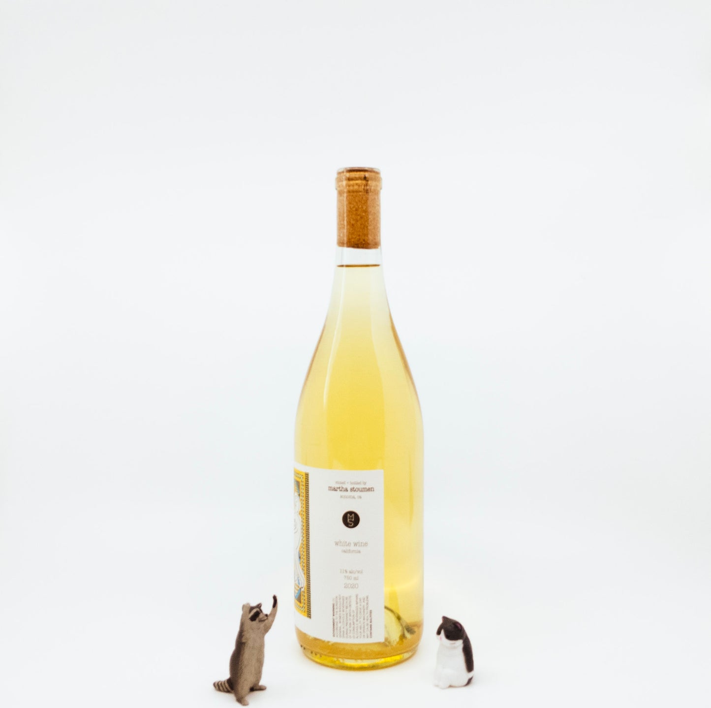 back of wine bottle next to raccoon and cat figurines