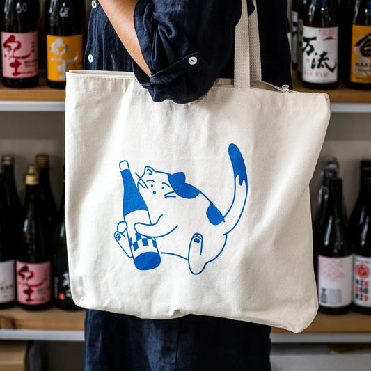 tote bag with blue outline of a cat holding a bottle