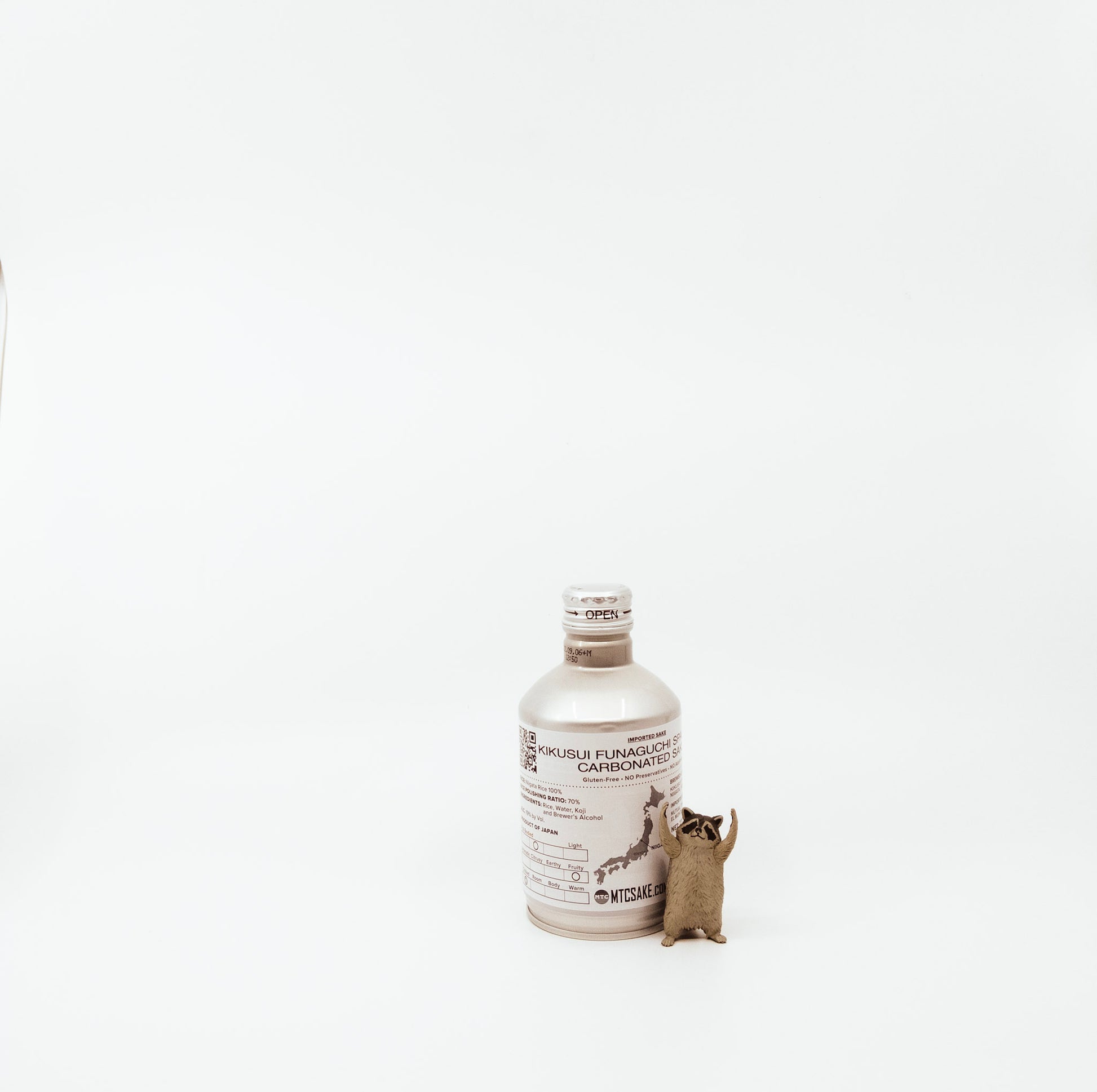 back of small white bottle next to raccoon figurine