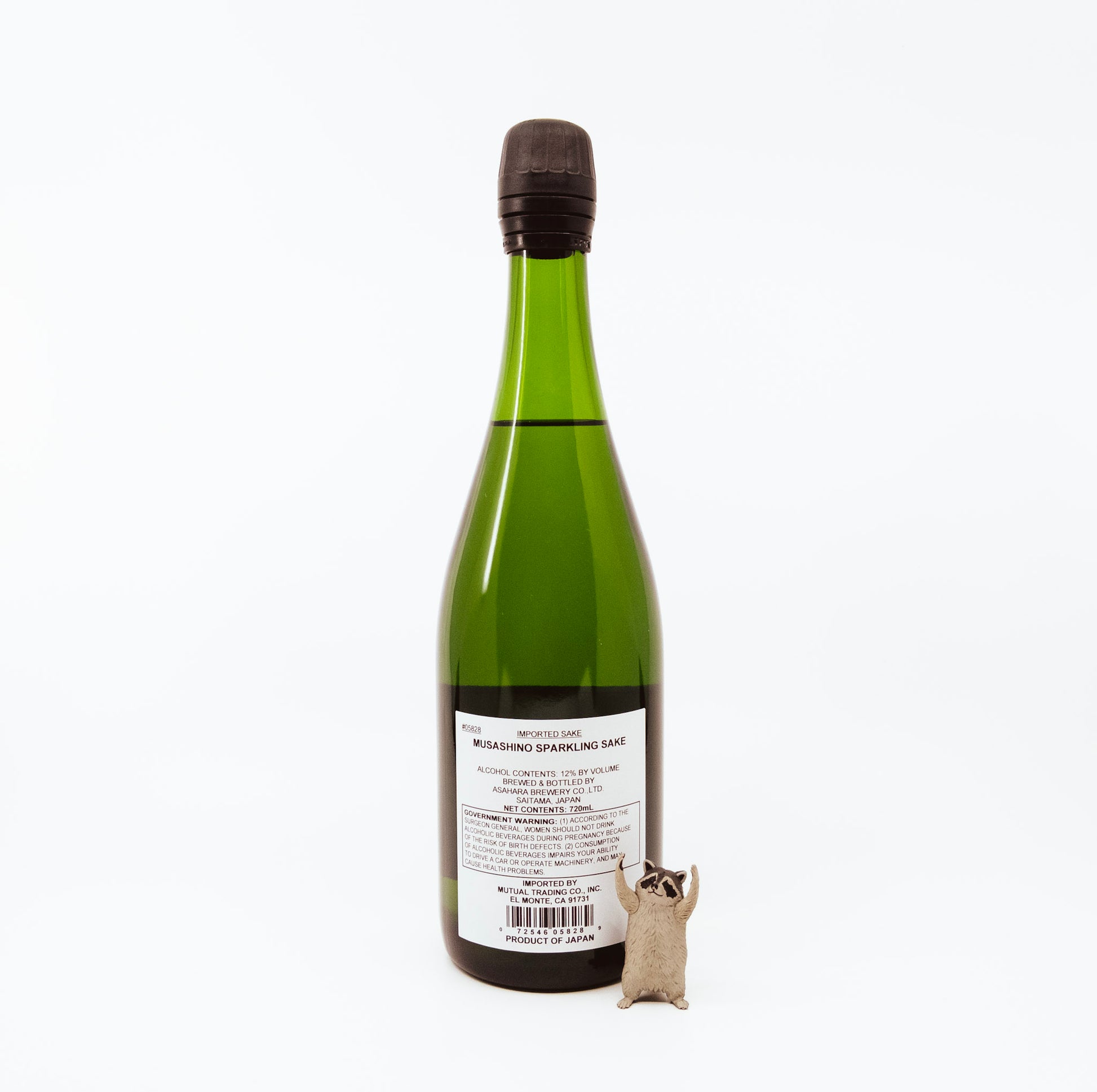 back of green glass bottle next to raccoon figurine