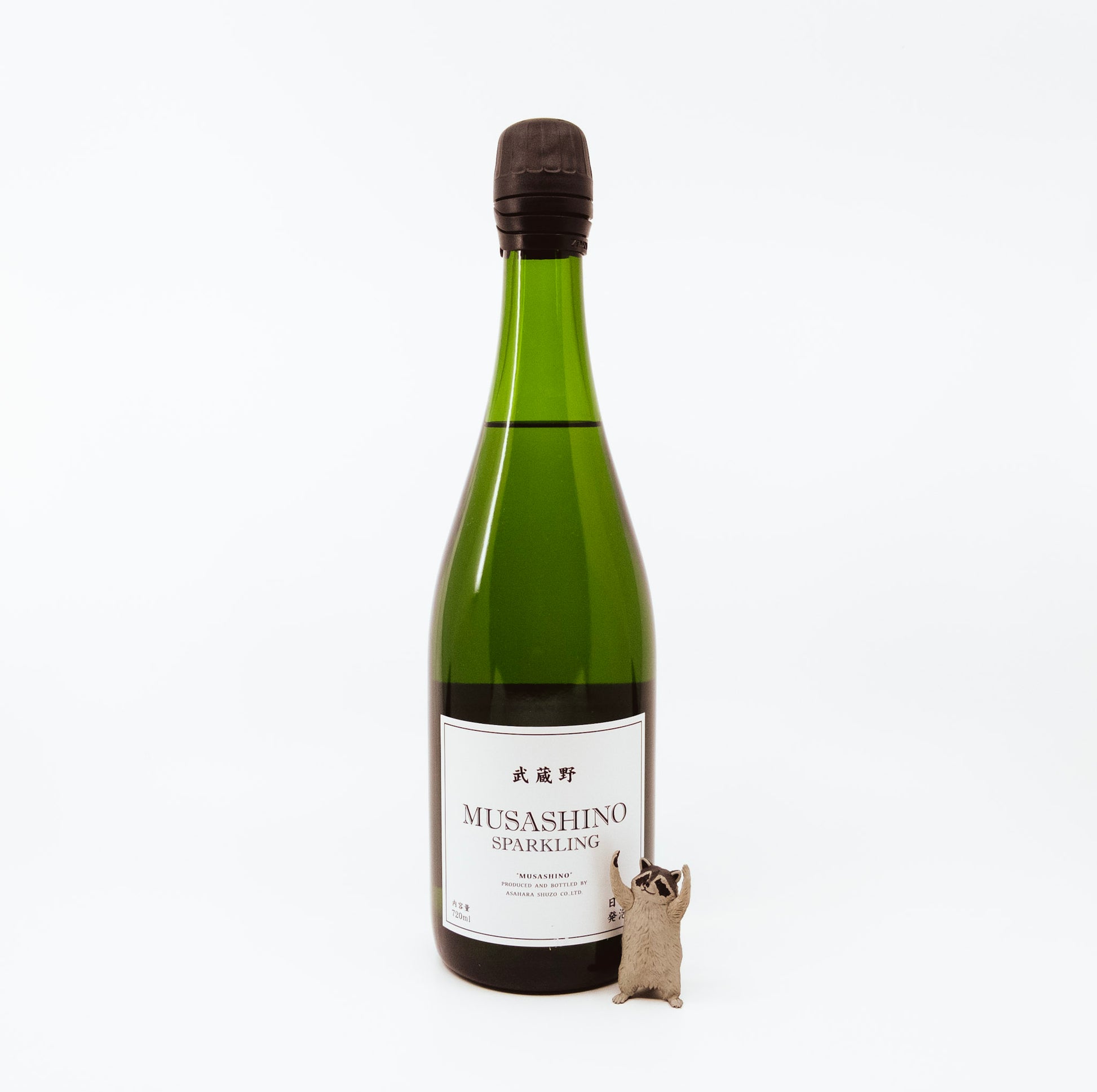 green glass bottle next to raccoon figurine