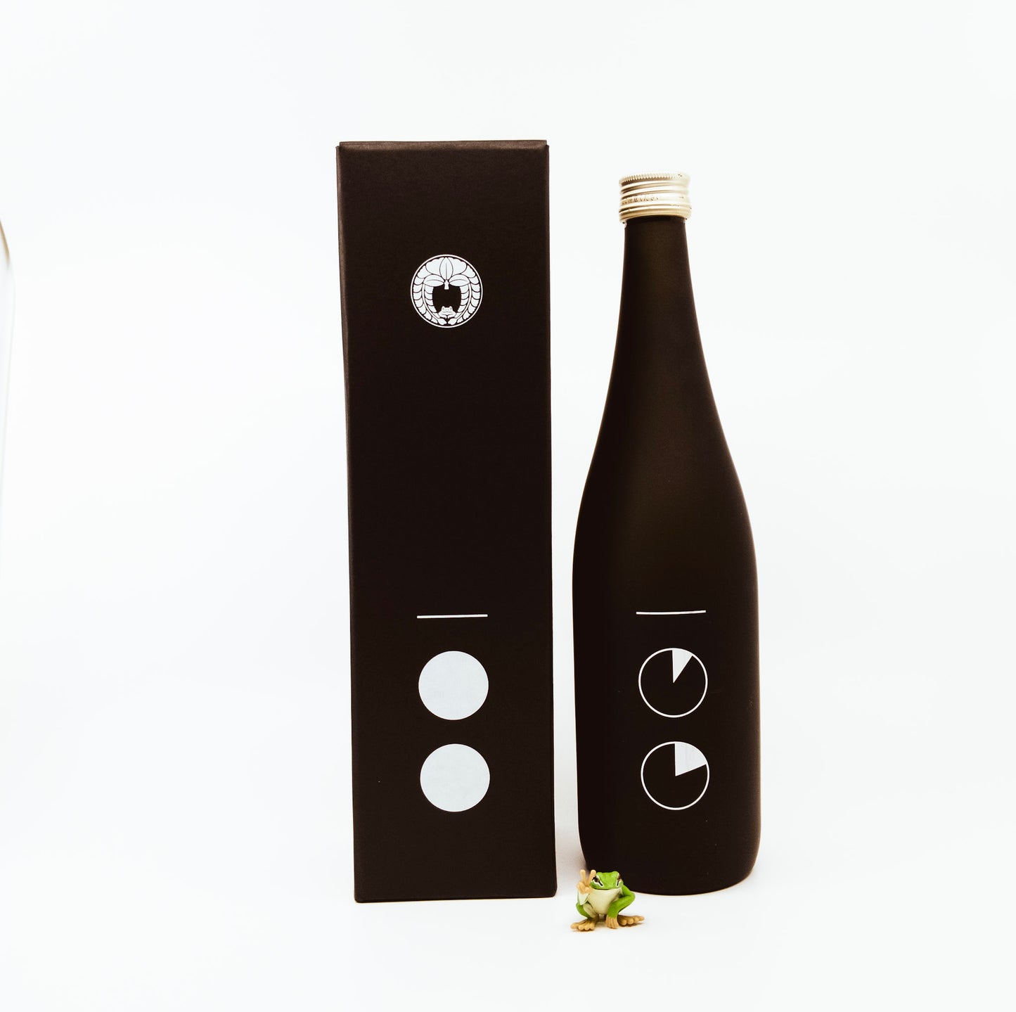 black bottle next to box and frog figurine